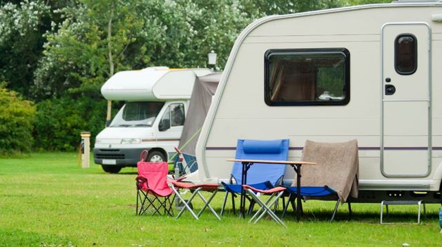 Motorhome and caravan with deckchairs at a campsite